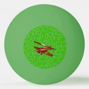 Rotes Doppeldeckerflugzeug auf grünen Kreisen und  Tischtennisball