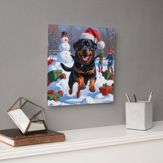Rottweiler läuft im Schnee mit Weihnachtshut Quadratische Wanduhr (Büro)