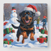 Rottweiler läuft im Schnee mit Weihnachtshut Quadratische Wanduhr (Vorderseite)