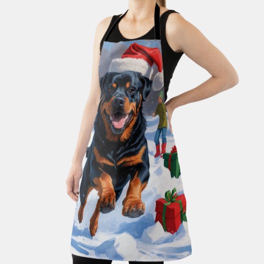 Rottweiler läuft im Schnee mit Weihnachtshut Schürze (InSitu)