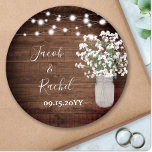 Rustikale Blumenmason Jar & Lights Hochzeit Runder Aufkleber<br><div class="desc">Dieses Design besticht durch die atemberaubende Blume eines farbigen Aquarellbabys in einer Glaskeramikvase auf einem rustikalen Holzhintergrund mit Saitenbeleuchtung. Klicken Sie auf die Schaltfläche Anpassen, um den Text zu verändern oder die Grafik zu verschieben! Variationen dieses Designs sowie der Koordinationsprodukte sind in unserem Shop, zazzle.com/doodlelulu*, erhältlich. Kontaktieren Sie uns, wenn...</div>