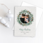 Rustikales Winter Greenery Wreath White Wood Foto Feiertagskarte<br><div class="desc">Elegantes "Frohe Weihnachten" Fotokartendesign mit rustikalem,  elegantem,  weißem Holzkornhintergrund mit einem runden Kranz aus Winterwasserfarbengrün,  der das Familienbild umrahmt und die moderne grüne und kohlegraue Formulierung betont. Personalisieren Sie mit Ihrem Nachnamen und dem Jahr. Enthält eine zusätzliche Meldung mit Familiennamen und Bonuslandschafts-Foto auf der Kartenrückseite.</div>