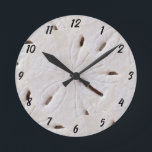 Sand Dollar Beach Seashells Muschel Beach Deco Runde Wanduhr<br><div class="desc">Das Hotel ist mit dem Bild von Sand-Dollar-Mustern im Hintergrund gestaltet und eignet sich perfekt für die Dekoration von Strandhäusern oder Weihnachten,  für Urlaubsgeschenke!</div>