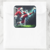 Santa Kicks a Soccer Ball in festlicher Atmosphäre Quadratischer Aufkleber (Tasche)