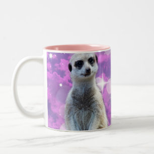Schimmernder Charme: Meerkat auf rosa Bokeh Hinter Zweifarbige Tasse