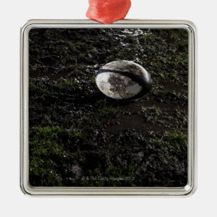 Schlammiger Rugbyball, der auf gekaut herauf Gras Ornament Aus Metall