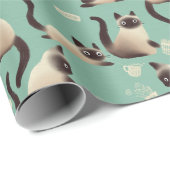 Schlechte siamesische Katzen klopfen über Geschenkpapier (Rolleneckpunkt)