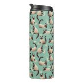 Schlechte siamesische Katzen klopfen über Thermosbecher (Nach rechts gedreht)