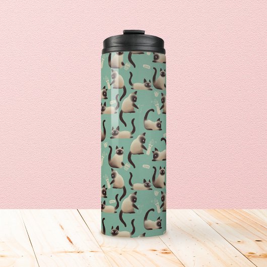 Schlechte siamesische Katzen klopfen über Thermosbecher