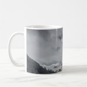SCHNEEBEDECKTER BERG UNTER BEWÖLKTEM HIMMEL WÄHREN KAFFEETASSE