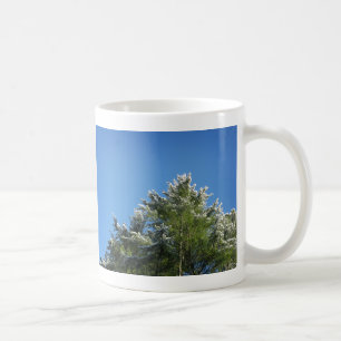 Schneebedeckter Kiefernbaum auf blauem Himmel Kaffeetasse