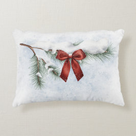 schneebedeckter Kiefernzweig mit festlichem rotem  Dekokissen