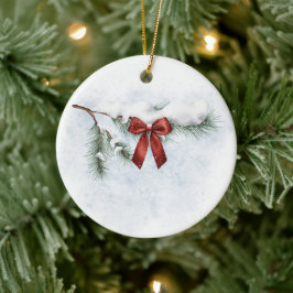 schneebedeckter Kiefernzweig mit festlichem rotem Keramik Ornament