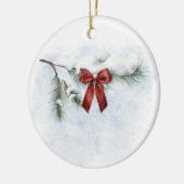 schneebedeckter Kiefernzweig mit festlichem rotem Keramik Ornament (Links)