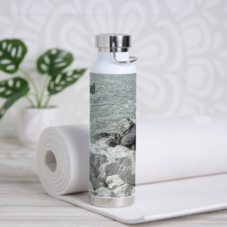Schwarz-Weiß-Foto eines felsigen Ozeans Uferwasser Trinkflasche