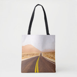 SCHWARZE ASPHALTSTRASSE INMITTEN DES BROWN-FELDES TASCHE