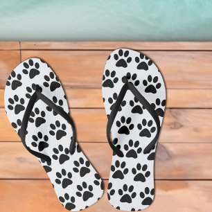 Schwarze Hundepfotenabdrücke auf Weiß Badesandalen