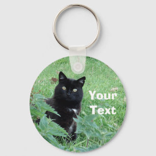 Schwarze Katze Halloweens im Gras schaut Schlüsselanhänger