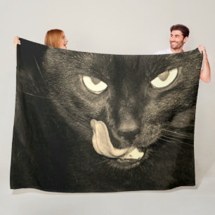 Schwarze Katze lecken Fleecedecke