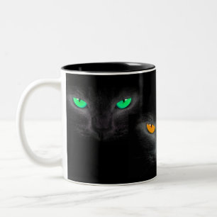 Schwarze Katze stellt gespenstische Zweifarbige Tasse