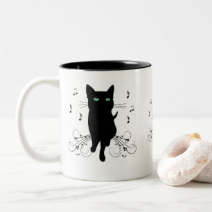 Schwarze Katze umgeben von flüsternden Noten der M Zweifarbige Tasse