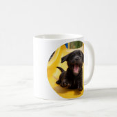 Schwarzer Labrador Retriever glücklicher Welpe auf Kaffeetasse (VorderseiteRechts)