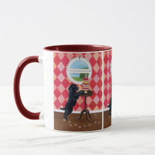 Schwarzer Labrador-Welpe mit kleinen Kuchen Tasse