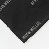 Schwarzes Fleeceblatt mit grauem Namen wiederholt Fleecedecke (Ecke)