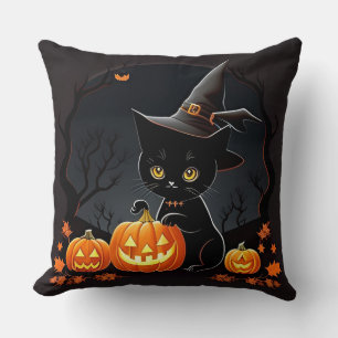 Schwarzes Kätzchen in Hexenhut zwischen Halloween- Kissen