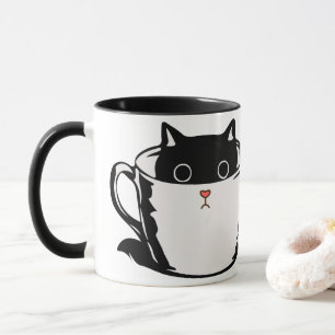 Schwarzes Kätzchen mit roter Nase, das sich in ein Tasse