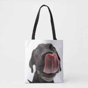 Schwarzes Labrador, das seine Nase leckt Tasche