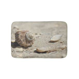 Seashells auf Sand durch das Meer Badematte