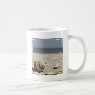 Seashells auf Sand durch das Meer Kaffeetasse