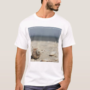 Seashells auf Sand durch das Meer T-Shirt