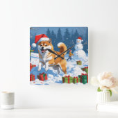 Shiba Inu läuft im Schnee mit Weihnachtsmütze Quadratische Wanduhr (Zuhause)
