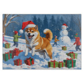 Shiba Inu läuft im Schnee mit Weihnachtsmütze Schneidebrett (Vorderseite)