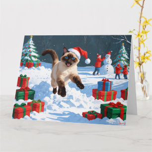 Siamese-Katze läuft im Schnee mit Weihnachtsmütze Karte