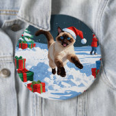 Siamische Katze läuft im Schnee mit Weihnachtsmütz Button (Beispiel)