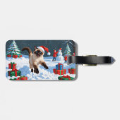 Siamische Katze läuft im Schnee mit Weihnachtsmütz Gepäckanhänger (Rückseite horizontal)