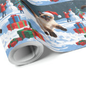 Siamische Katze läuft im Schnee mit Weihnachtsmütz Geschenkpapier (Rolleneckpunkt)