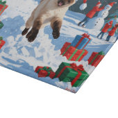 Siamische Katze läuft im Schnee mit Weihnachtsmütz Schneidebrett (Ecke)