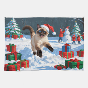 Siamkatze läuft im Schnee mit Weihnachtsmütze Geschirrtuch