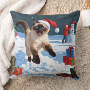 Siamkatze läuft im Schnee mit Weihnachtsmütze Kissen