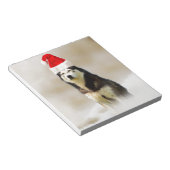 Siberischer Husky-Hund mit Weihnachtsmannmütze im Notizblock (angewinkelt)