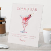 Sie bindet das Knot-Pink-Coquette-Cosmo-Bar Sockelschild (In Situ)