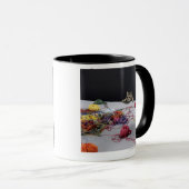 Silberne Tabbykatze, die über Rand der Tabelle Tasse (VorderseiteRechts)