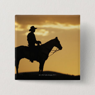 Silhouette des Cowboys auf Pferderuecken am Button
