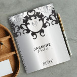 Silver and Black Glam Elegant Trendy Jahr Planer<br><div class="desc">Dieser elegante und raffinierte Planer behalte Sie das ganze Jahr über organisiert und inspiriert. Das silberne, metallische Cover ist mit verzierten, schwarz-grauen Designs an der Oberseite und unten geschmückt, was eine Touch von Klasse und Stil hinzufügt. Im Mittelpunkt des Covers steht ein Schilddesign, das Schutz und Kraft symbolisiert, mit einem...</div>