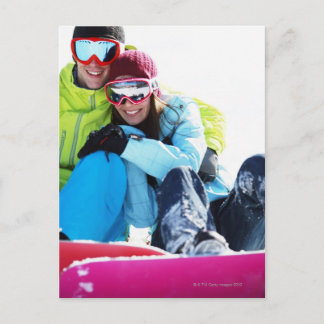 Snowboarderpaare, die auf Schnee sitzen Postkarte