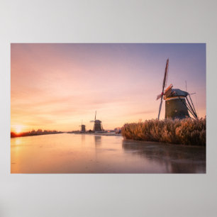 Sonnenaufgang über gefrorenem Fluss mit Windmühlen Poster